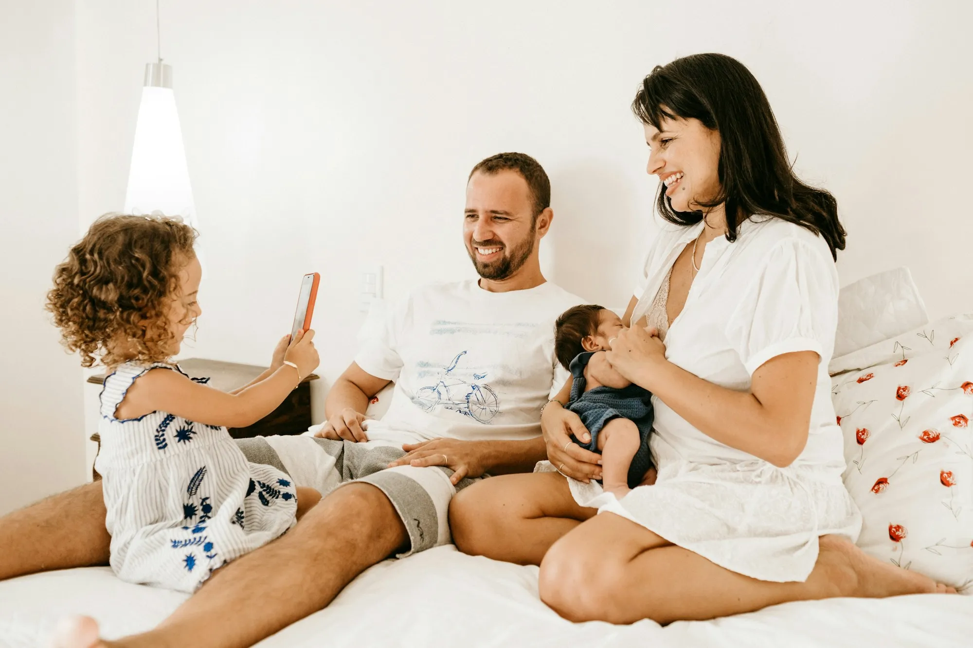 A family relaxing together on a bed with their baby and toddler