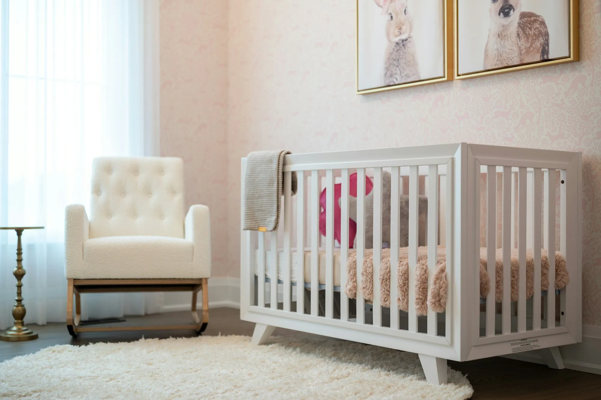 A bright nursery with a white crib and an upholstered glider